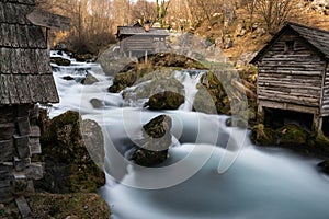 Mountain river with mossy rocks and wooden watermills in long exposure