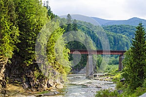 Mountain river with a rapid current of rocks and a bridge