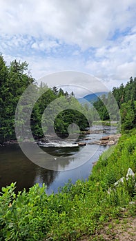 Mountain river rapids in rocky waters creek with mountains clouds and Evergreen forests in Adirondack Park New York