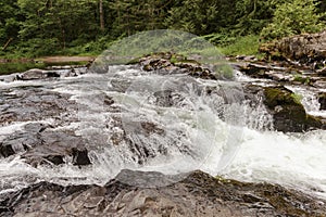 Mountain river with small waterfall, rocks, forest