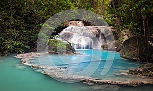 Mountain river stream flows through tropical forest and falls photo