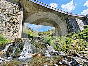 Mountain river water flowing under a bridge.