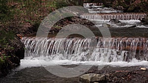 Mountain river with waterfalls and rapids flowing between rocky banks