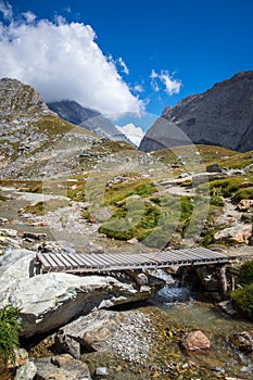 Mountain river and wood bridge in Vanoise national Park valley, French alps