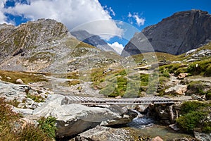 Mountain river and wood bridge in Vanoise national Park valley, French alps