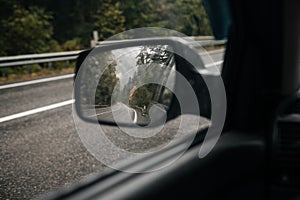 mountain road in autumn in the rain in the car mirror
