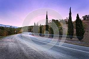 Mountain road with blurred cars in motion at sunset