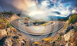 Mountain road at colorful sunset in summer. Curved roadway
