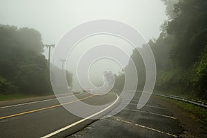 A mountain road covered by fog causing limited visibility