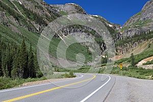 Mountain road curves in front of large mountains in Colorado.