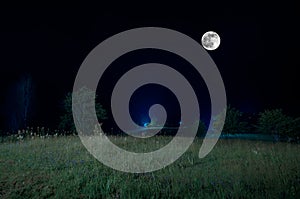 Mountain Road through the forest on a full moon night. Scenic night landscape of dark blue sky with moon