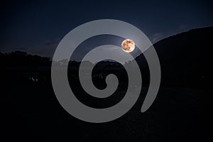 Mountain Road through the forest on a full moon night. Scenic night landscape of dark blue sky with moon. Azerbaijan