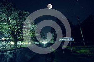 Mountain Road through the forest on a full moon night. Scenic night landscape of dark blue sky with moon. Azerbaijan. Long shutter