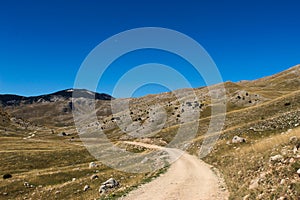 The mountain road and the rocky landscape of the Bjelasnica mountain. In the background, the top of the mountain mountain photo