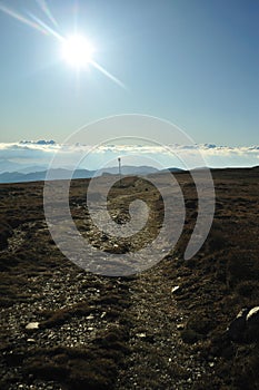 Mountain road with sun in front and marking pole