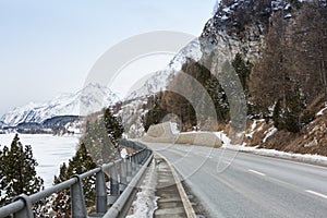 Mountain road in Swiss alps at an overcast winter day. Val Bregaglia, canton Graubunden, Switzerland