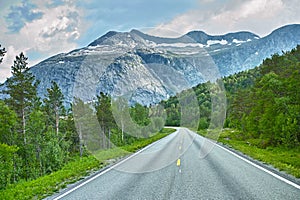 Mountain, road trip and forest highway with travel, holiday and countryside scenery in Norway. Nature, clouds in sky and