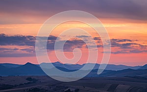 Mountain rural landscape with colored clouds on a sky during a s