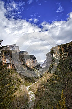 Mountain scenery with a river flowing through it on a sunny day with cotton clouds photo