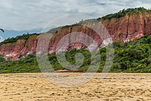 Mountain by the sea, with waves, vegetation and blue sky around.