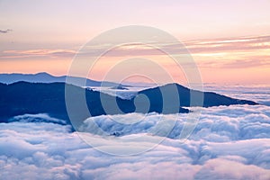Mountain silhouette above the clouds at sunrise, view from the t