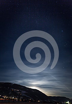 Mountain silhouette against starry nigh sky and shining moon