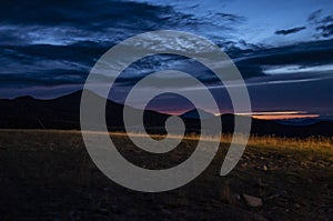 Mountain silhouette and meadows at sunset