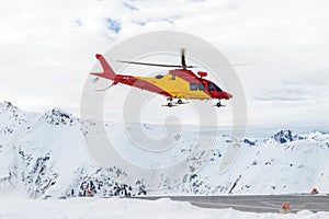 Mountain ski life rescue medic helicopter taking-off from station helipad to search injured skiers and help at accident