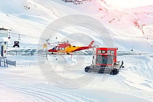 Mountain ski life rescue station with heavy machinery. Helicopter, snowcat and snowmobile standby ready to save tourist in