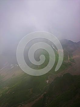 Mountain slope with cable cars and ski slopes on a cloudy summer day, fog, clouds. Black Pyramid Mountain, Krasnaya Polyana, Sochi