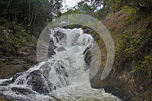 Between the mountain slopes a waterfall rages and foams on the stones.