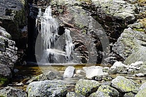 Small waterfall and blurred stream between rocks.