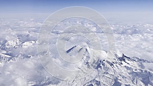 Mountain snow landscape nature from the height of an airplane in the winter season. Snow-covered peak of the mountain range is wra