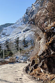 Mountain with snow and leaves less trees. Below with dirt road and four wheel drive tourist car on the way to Zero Point