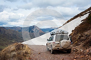 Mountain snow road landscape. 4x4 jeep car on a mountain pass, mount peak. End of the road in the mountains. Road blockage.