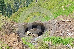 A mountain stream cut a tunnel through the remnant of an avalanche
