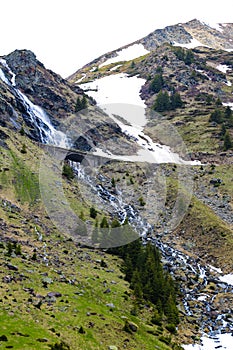 Horský potok teče po úbočí hory, sníh. Přírodní pozadí na jaře nebo v létě. Selektivní zaměření