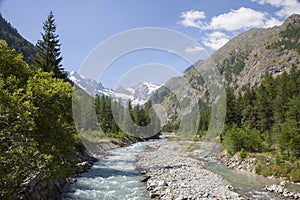 Mountain stream in italian national park gran paradiso with snow capped mountains in the background