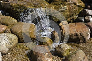 A mountain stream pours on the stones. Waterfall in the river. Rapids on the stream