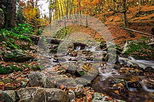 Mountain stream with waterfall in an autumn forest.