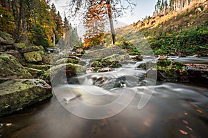 Mountain stream with waterfall in an autumn forest.