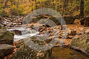 Mountain stream with waterfall in an autumn forest