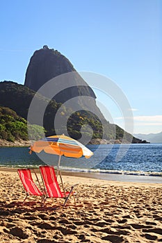 Mountain Sugarloaf sun umbrella and chairs on red beach (Praia