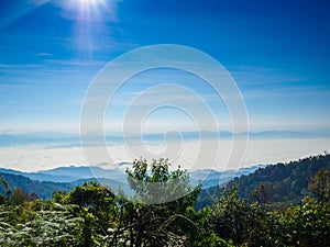 Mountain terrain in a sea of mist, on cloudy sky with sunlight .