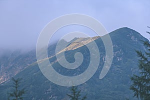 Mountain tops in autumn covered in mist or clouds in sunrise li