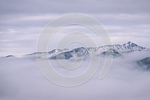 Vrcholy hôr na jeseň zahalené v hmle alebo oblakoch - vintage effe
