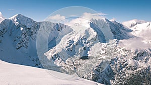 Mountain tops in winter covered in snow with bright sun and blue