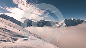 Mountain tops in winter covered in snow with bright sun and blue