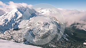 Mountain tops in winter covered in snow with bright sun and blue