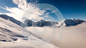 Mountain tops in winter covered in snow with bright sun and blue